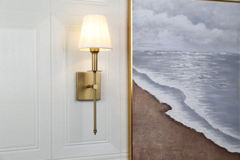 Wall with a mounted set of 2 Rustic Industrial Wall Sconces with flared white textile shade and antique brass tapered column stand
