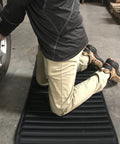 Person kneeling on VersaMat Roll Up Workhorse High Density Foam Utility Mat Black For Garage And Home 1 Inch Thick Closed Cell Foam