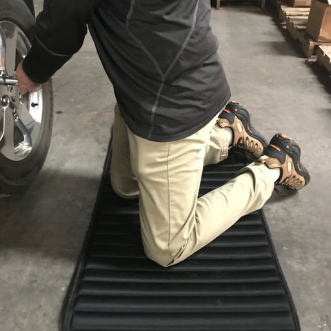 Person kneeling on VersaMat Roll Up Workhorse High Density Foam Utility Mat Black For Garage And Home 1 Inch Thick Closed Cell Foam