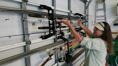 Person using Garage Door Organizer Rack for Fishing Gear and Tools 18 Inch ABS Plastic Rod Holder Ultimate Garage Storage System.