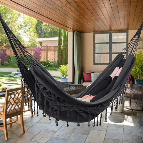 Person relaxing in Boho Macrame Hammock With Elegant Tassels For Patio And Yard Cozy And Chill For Indoor Or Outdoor Use 450 Pound Capacity