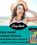 Woman with beach hat smiling, holding ChapStick Sweet Watermelon Lip Balm Trio, Peaches And Cream Lip Balm, Pink Lemonade Lip Balm, 0.15 oz, three pack.