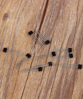 Hall Effect Switches Pack Of 10 A3144 Magnetic Hall Sensor, 3 Pin SIP Inline Detector scattered on wooden surface.