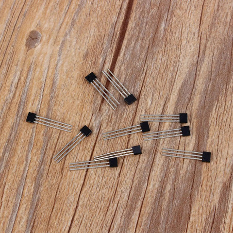 Hall Effect Switches Pack Of 10 A3144 Magnetic Hall Sensor, 3 Pin SIP Inline Detector scattered on wooden surface.