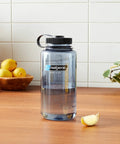 Rugged 32 Oz Wide Mouth Reusable Water Bottle With Tight Seal Black Lid on a wooden table with lemons.