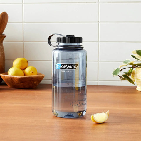 Rugged 32 Oz Wide Mouth Reusable Water Bottle With Tight Seal Black Lid on a wooden table with lemons.