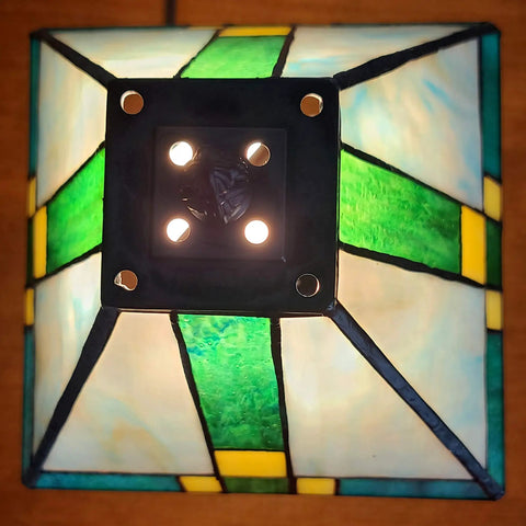 Top view of Tiffany Style Table Lamp With Stained Glass Mission Glass Panels In Rich Colors For Classic Living Room Or Bedroom Decor 8 Inch Shade 14 Inch Total Height Sturdy Metal Base Warm Ambient Glow Model AM354TL08, showing green, yellow, and blue panels.