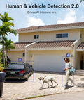 Residential area with a parked car, a person walking a dog in front of a house, demonstrating AI motion detection capabilities.