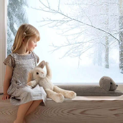 Heavy Duty Door Draft Stopper To Keep The Chill Outta Your Space by a child sitting on a window ledge with stuffed animals.