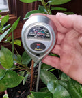 Person holding Moisture, Light And pH Soil Test Meter for Garden, Lawn And Indoor Pots, measuring soil in potted plant
