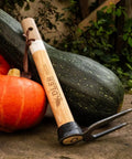 Heritage Garden Fork For Weeding And Digging with 11.8 inch handle leaning on pumpkins, showcasing heavy duty wood and dual-forged prongs.