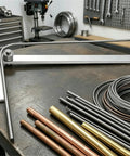 Electric Mini Rebar Bender And Pipe Tube Bending Tool shown with various metal rods on a workbench, ideal for job sites.