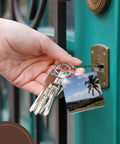 Hand holding keys with Outrigger Fishing Canoe Key Chain Set From Fiji Bright Multicolor Print Heavy Duty Plastic High Gloss Finish Dual Sided Image Includes Hardware 2 Pack in door lock