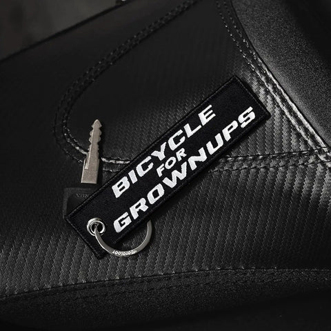 Dope Bicycle For Grownups Keychain For Riders on black leather with key; pocket sized, metal ring visible.