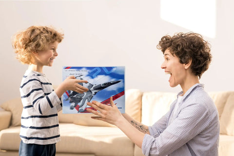 Child handing Beginner Friendly 2CH RC Plane Ready To Fly Hobby Glider with Luminous Yellow Strip to smiling adult indoors