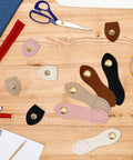 Colorful 15 Piece Leather Snap Buckles Set For Purses And Bags, Sew On Button Closures, displayed on wooden surface with sewing tools.