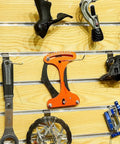 Orange Bike Spoke Tension Meter And Spoke Wrench Kit for Road And Mountain Bikes displayed on a wooden wall.