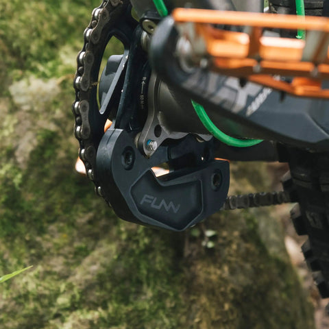 Close-up of a Zippa Lite MTB Bash Guard for ISCG05 Mount Fits 26T To 32T Chainrings on a bike chainring in nature.