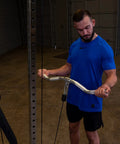 Man using Straight Up Heavy Duty Aluminum Curl Bar Attachment Compatible With Cable Machines in home gym.