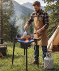 Man cooking on Single Burner Outdoor Propane Gas Stove 100,000 BTU LPG Camping Cooker With Tall Stand And PSI Regulator in campsite