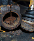 Ball joint puller components: two rusted parts, hollow sleeve and adjacent ball joint with rubber boot