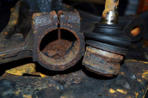 Ball joint puller components: two rusted parts, hollow sleeve and adjacent ball joint with rubber boot