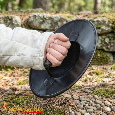 Hand holding Beefy Battle Ready 11 Inch Small Medieval Buckler Shield With Rolled Rim And Riveted Grip 16 Gauge Mild Steel