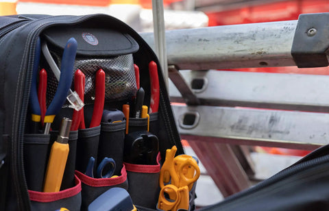 ToolPack Pro Backpack For Roofers, Electricians, Data Techs, Glaziers, And Handymen The All In One Heavy Duty Tool Bag Backpack With Ample Pockets Easy Access Durable Build And Comfortable Straps Ready For Any Job Site filled with tools and positioned by ladder