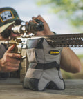 Tactical DeadShot Front And Rear Rifle Rest Combo on table with shooter aiming, filled and range ready, heavy duty ballistic nylon.