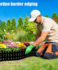 Man installing Flexible Garden Edging Border Kit 33 Ft Black Lawn Edging With 60 Stakes, 4.7 In Tall, around a flower bed