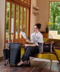 Woman sitting with 5 piece travel luggage set including carry-on and duffel in stylish living room.