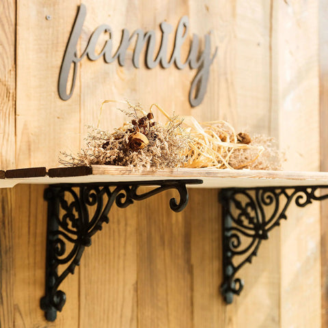 Heavy Duty Wrought Iron Shelf Brackets Two Pack Antique Black Corbels under a wooden shelf with dried flowers.