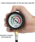 Hand holding exhaust back pressure tester gauge showing psi and bar readings with color bands