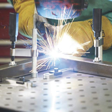 Welder using 4 Piece Welding Table Clamp Kit With Lightweight Aluminum Frame And ABS Handle, Easy Setup And Adjustable 4 Inch Throat Depth, Fits 16mm Hole Tables For Secure Hold, Black Metallic Finish on metal surface with sparks