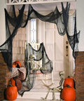 Six Pack Matte Black Cotton Crepe Sheets draped on porch with skeletons and pumpkins for Halloween decor.