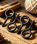 10 Pack Tough As Nails M6 Eye Screws 2.2 Inch Black Heavy Duty Carbon Steel Self Tapping Screw Eye Hooks on wood surface.