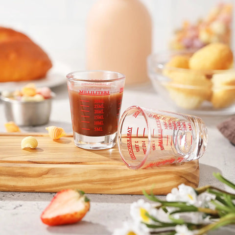 Two Pack Shot Glass Measuring Cup Set with thick base, one filled with liquid, showing four measuring scales for precise pouring
