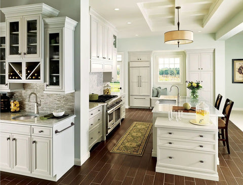 Modern kitchen with white cabinets, stainless steel appliances, and a kitchen island topped with a vase of yellow flowers.