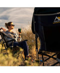 Woman relaxing in Ultra Easy Fold Up Outdoor Camping Chair For Adults With Mesh Back And Wide Seat Sturdy Powder Coated Steel Frame.