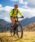 Cyclist riding a mountain bike on grassy terrain, showcasing durable tires for Two Pack Heavy Duty Bike Tire Inner Tubes 26 By 1 3 Eighths Inches AV32mm Schrader Valve 37-590 ETRTO Compatible Replacement Tubes For 26 By 1 3 Eighths Inches Wheels Ride Ready Tough As Nails.