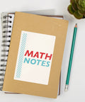 Notebook cover labeled 'MATH NOTES' with colorful text, green pencil, and succulent plant on a white surface.