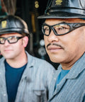 Workers wearing safety glasses and hard hats in an industrial setting.