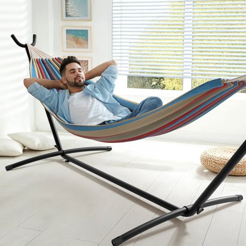 Two Person Luxury Hammock With Steel Stand Portable 450 Lbs Capacity Cotton Blend 60 Inch Bed indoors with man relaxing