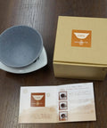 Premium Japanese Ceramic Coffee Filter Reusable Pour Over Dripper With Rock Solid Brown Holder next to packaging and instructions.