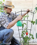 Man adjusting 4 Pack 32 Inch Metal Plant Trellis for Pots and Garden Beds, Rock Solid Rustproof Indoor Outdoor Climbing Support in garden