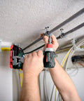 Person using Badass 18 Volt Cordless Brushless Drill Driver delivering 60 Newton Meters of torque for electrical installation.