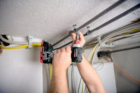 Person using Badass 18 Volt Cordless Brushless Drill Driver delivering 60 Newton Meters of torque for electrical installation.