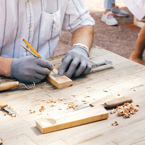 Person using Super Handy Flexible Stainless Steel Pocket Ruler Set With Detachable Clips, 6 Inch And 15 Cm Dual Metric And English Scales, Sliding Pocket Clip Gauge For DIY Woodworking Craft And Precise Measurements on a wooden block at a table, wearing gloves.