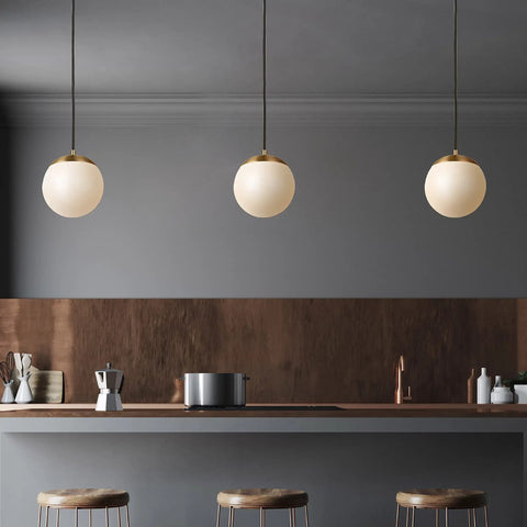 Trio of Leo Hanging Globe Pendant Light In Satin Brass Finish above a kitchen island