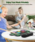 Child using Roll Up 9 Pad MIDI Electronic Drum Set With Headphone Jack Built In Dual Speakers on table, adult reading, headphones on.